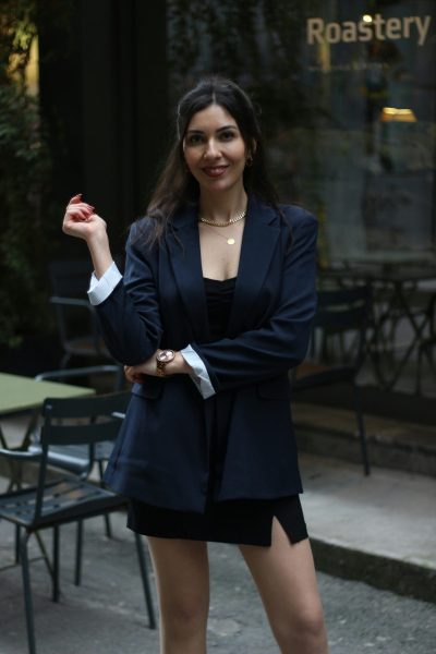 Fashionably dressed woman in Istanbul standing confidently outside a roastery.
